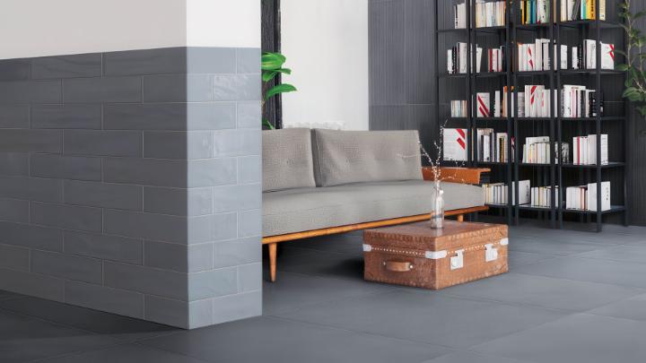 Modern living room featuring Obsidian Nimbus 6x24 gray glossy ceramic subway tile accent wall with gray floor tiles and contemporary furniture