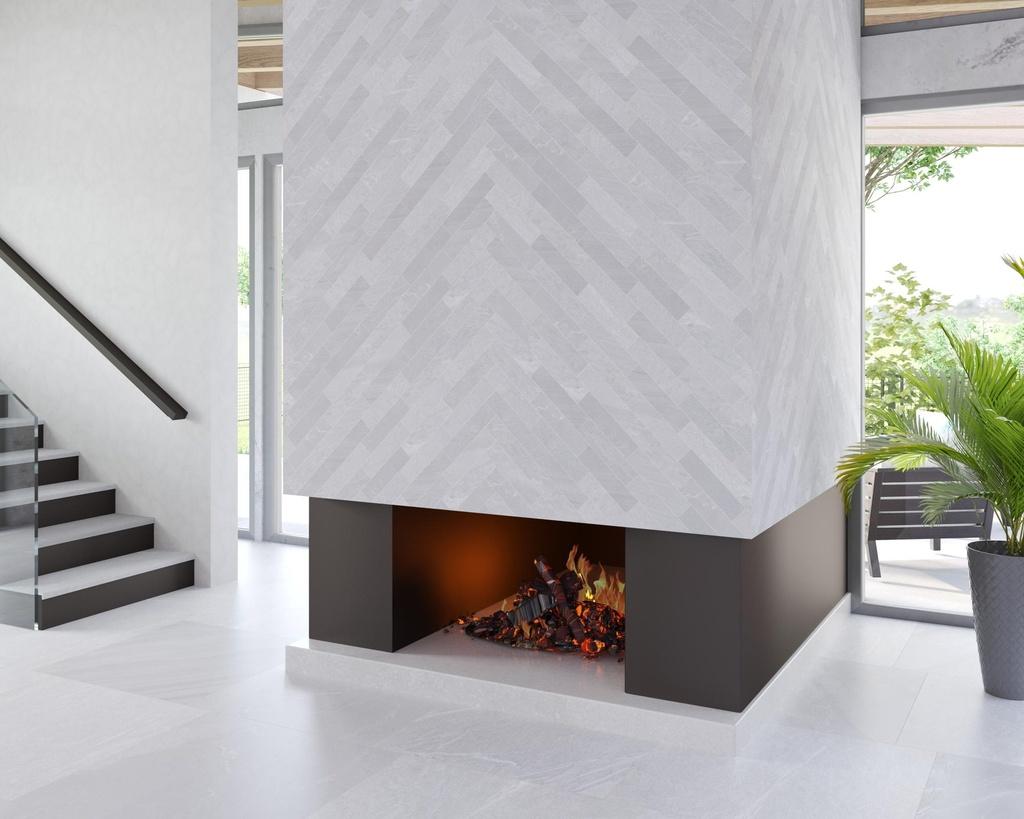 A modern living space featuring a tall fireplace with a light gray tile surround in a herringbone pattern. Flames are visible within the firebox. To the left, a minimalist staircase with dark treads and a glass railing ascends. Large windows overlook a patio with greenery.