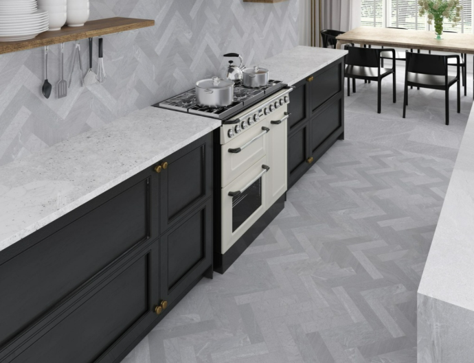 A light grey subway tile kitchen backsplash in a chevron pattern, shown in a modern kitchen with black cabinets and a cream-colored stove.