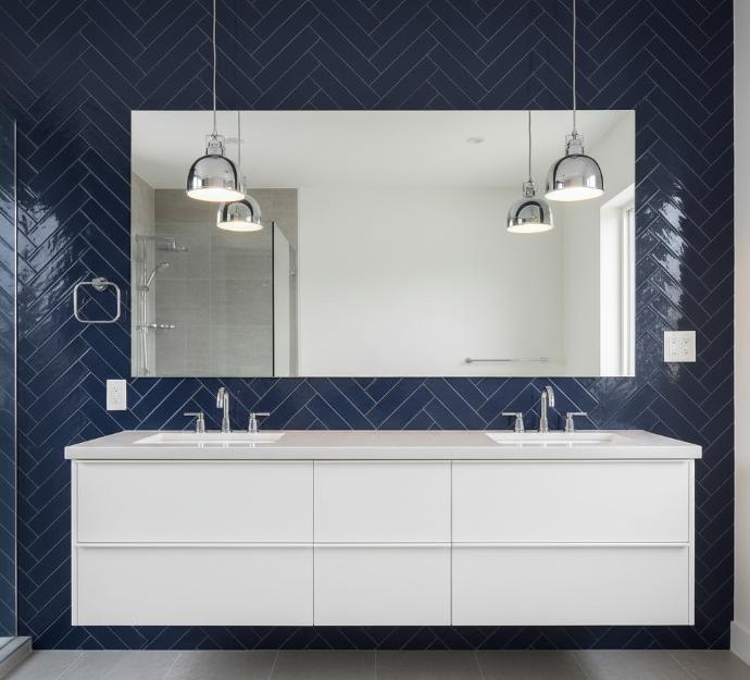 Herringbone pattern navy subway tile installation in contemporary bathroom with chrome fixtures and pendant lighting