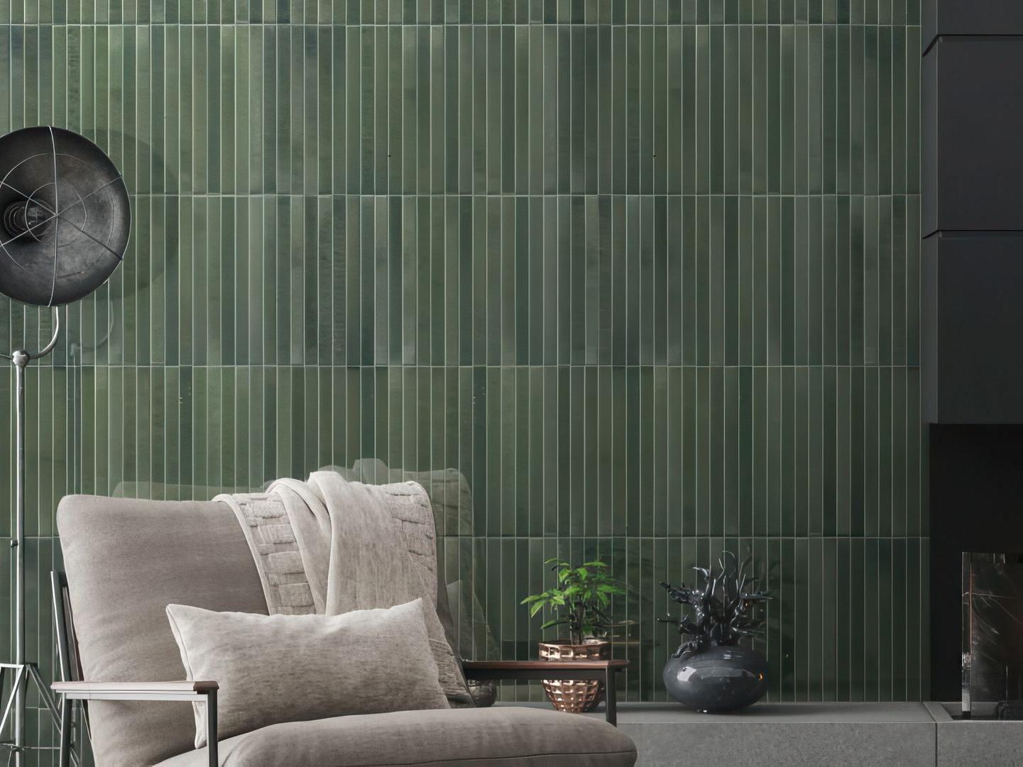 A modern living room feature wall covered in large format, glossy green subway tiles