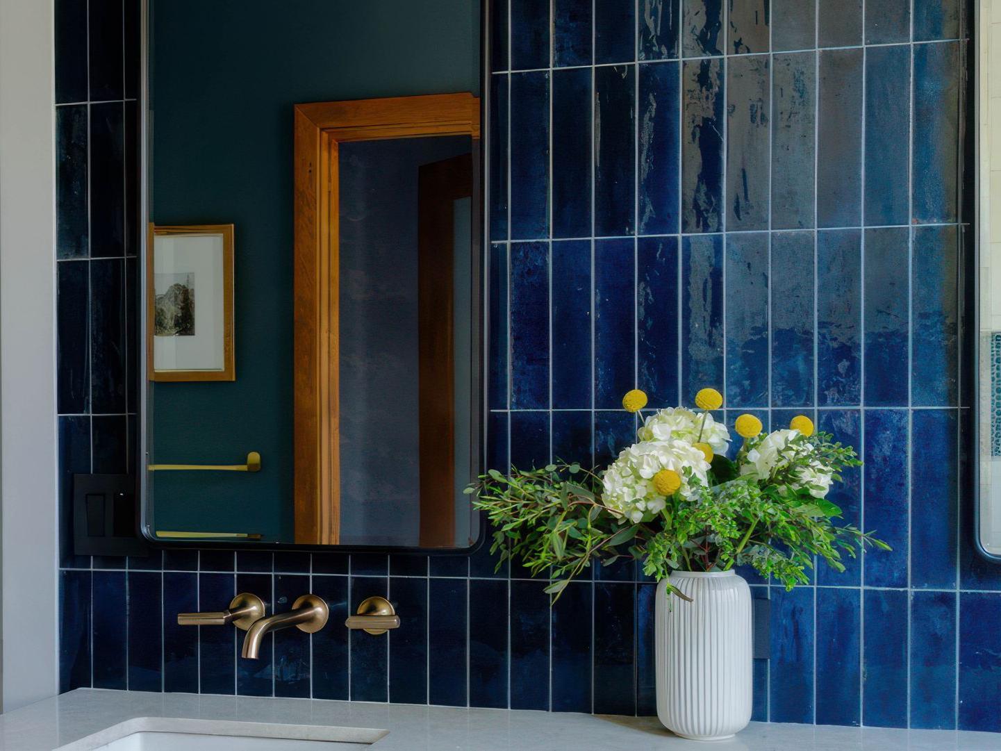 A modern bathroom wall featuring glossy, deep blue subway tiles