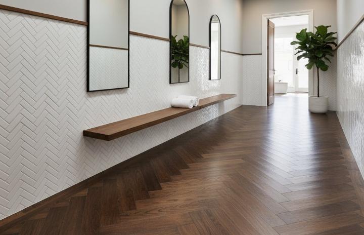 White subway tile wall in a herringbone pattern with dark wood flooring and a floating wooden bench in a hallway