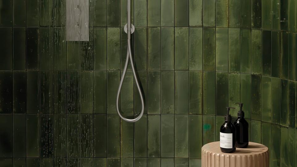 Dark green, Cyprus Glossy Subway Tile in a shower with a silver shower head and wooden stool.