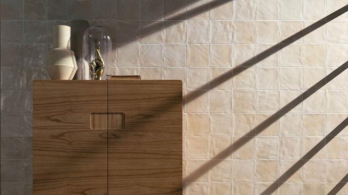 Rustic wooden cabinet against a wall of cream Zellige subway tiles with strong diagonal shadows.