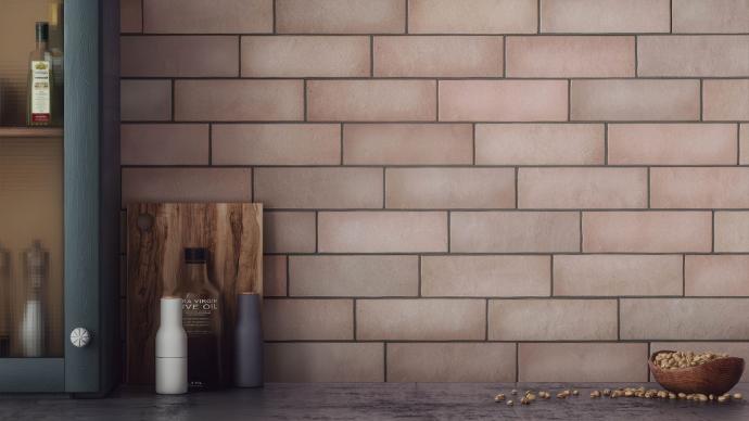 A close-up view of a kitchen backsplash tiled with matte, dusty-rose or terracotta-colored 2x8 subway tile