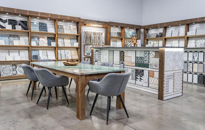 Nova Tile and Stone showroom displaying tile samples on wood shelves, with a central table and chairs.