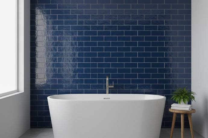 Glossy blue subway tile bathroom accent wall behind freestanding tub