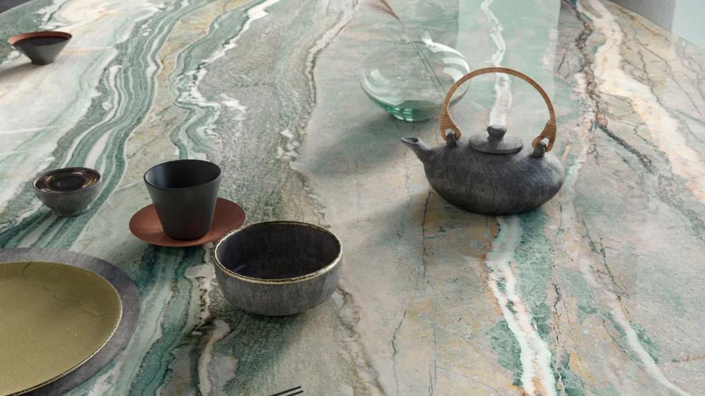 Close-up of Royal Peacock porcelain slabs countertop with tea set and flowing patterns.