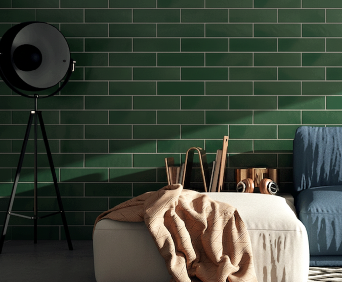 Green running bond subway tile wall with modern living room decor, featuring a floor lamp, ottoman, and cozy textiles.