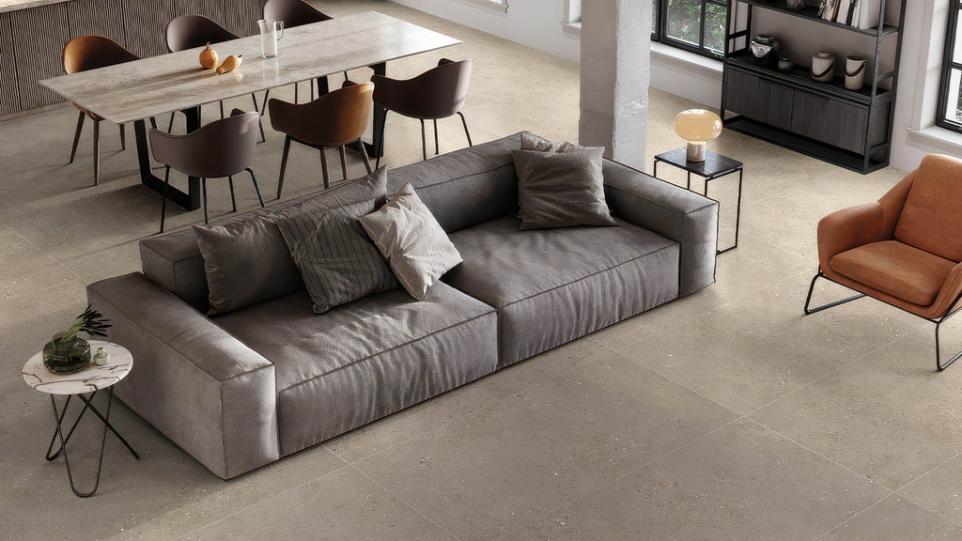 Living and dining area with City Sidewalk 24x48 Matte Cement Look Porcelain Tile and modern gray sofa.