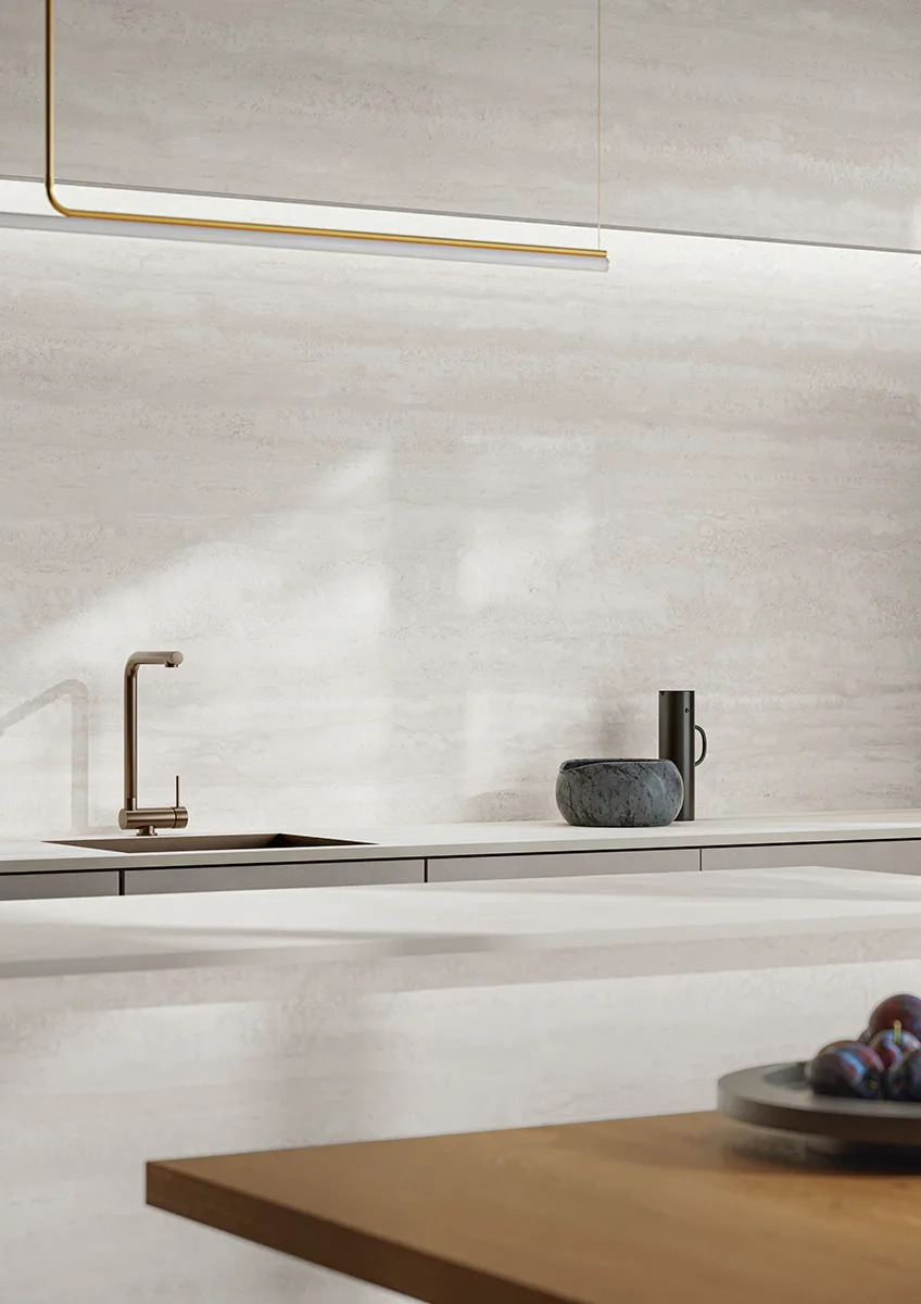 Minimalist kitchen with Travertino Bianco porcelain slabs on backsplash and walls with brass accents.