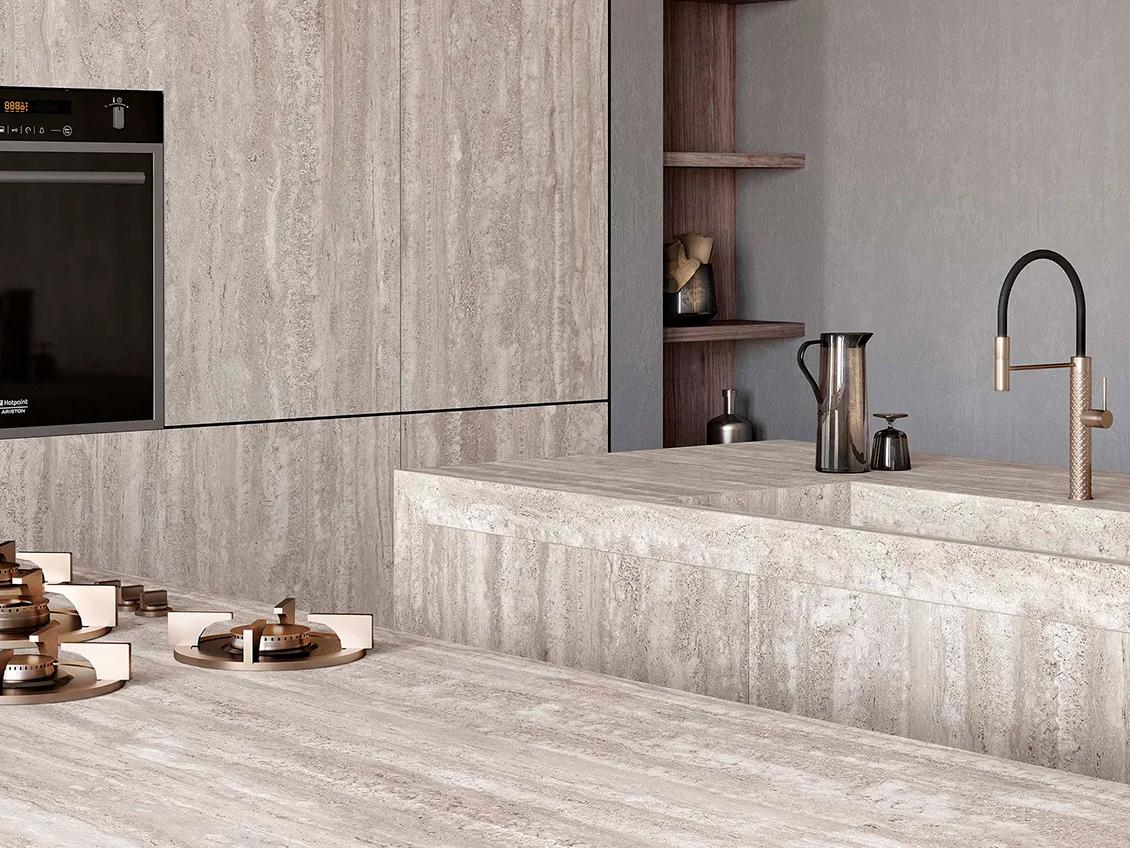 Travertino Chiaro porcelain slabs throughout modern kitchen with integrated sink island and built in appliances.
