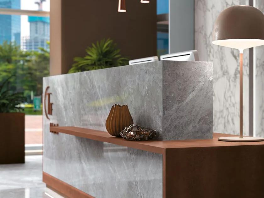Modern reception desk featuring Metal Corten porcelain slabs with warm wood accents and soft lighting