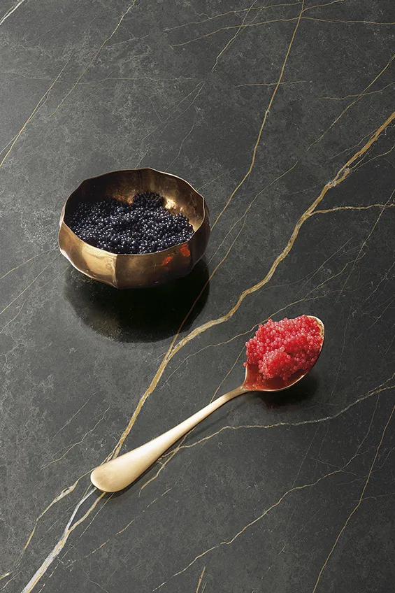 Floor application of Royal porcelain slabs featuring gold veins with decorative food styling.