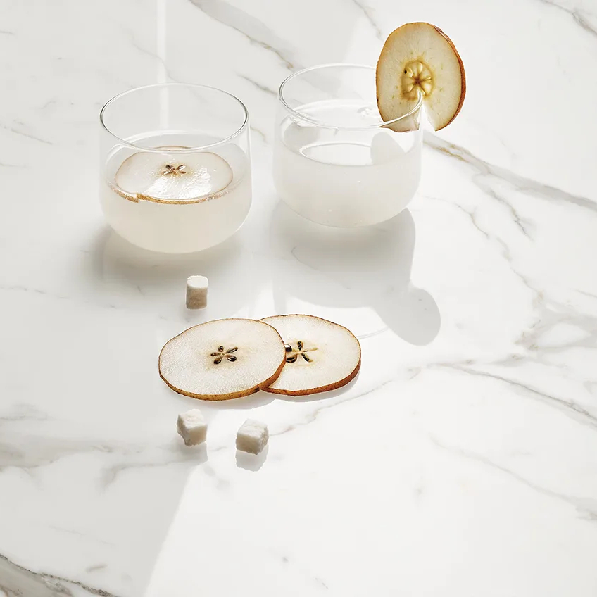 Défense porcelain slabs marble surface displaying sliced fruit desserts and modern white glassware.