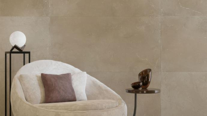 Modern living room featuring Aldridge Limestone Look Porcelain Tile in Sour color on walls with cream accent chair and minimalist decor