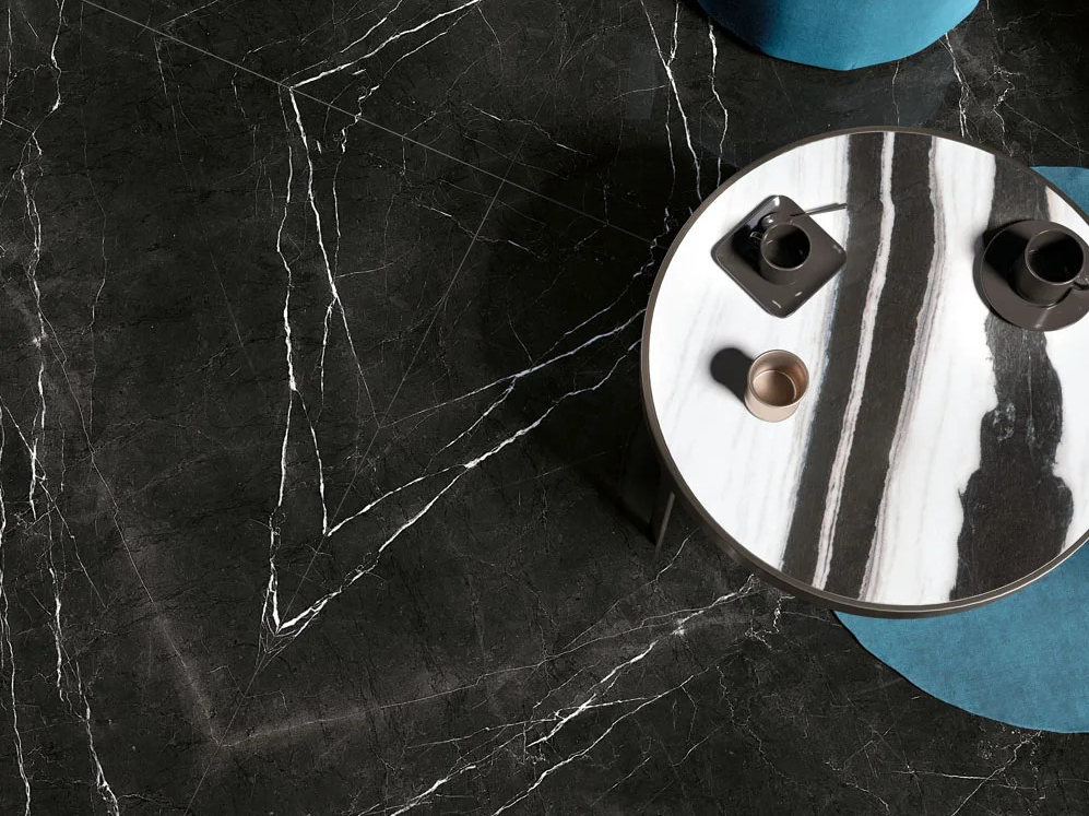 Round table made with Panda White porcelain slabs on dark marble floor setting.