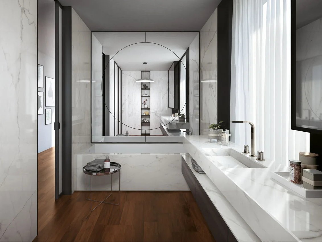 Calacatta Glory porcelain slabs installed in luxury bathroom with floating vanity and round mirror.