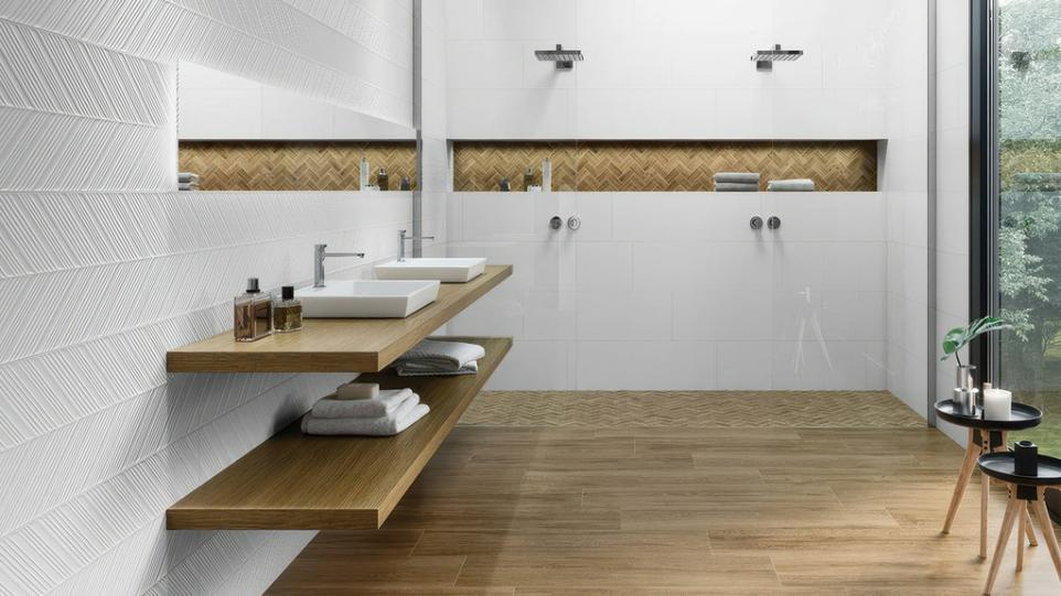 Modern bathroom featuring Prestige Arrow white ceramic wall tile with chevron pattern, wood-look floor tiles, and floating wood vanity