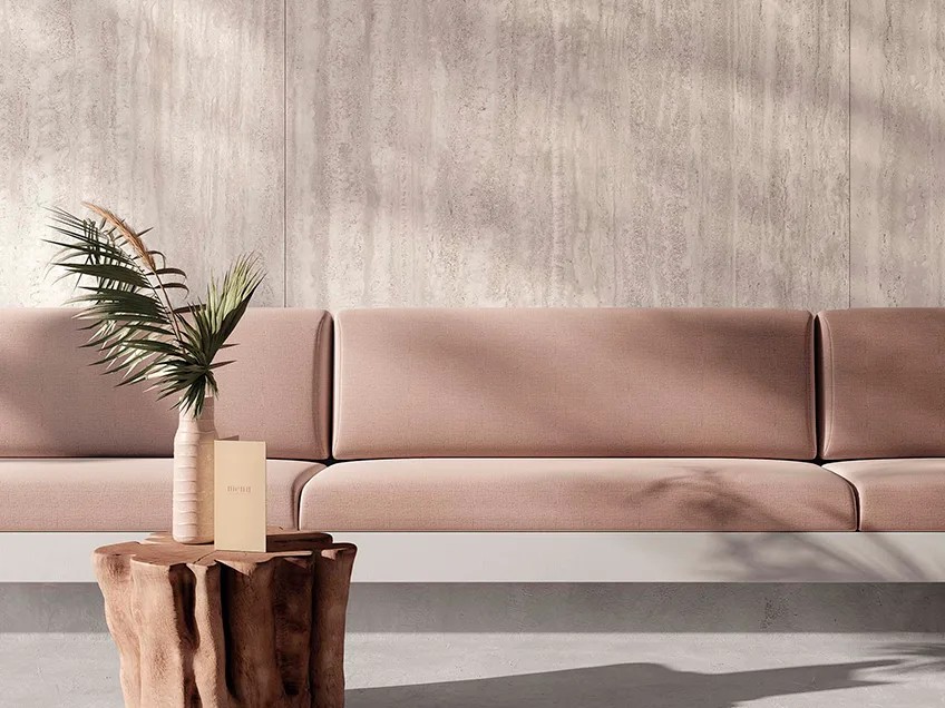 Travertino Chiaro porcelain slabs as feature wall backdrop with dusty rose sectional and wood side table.