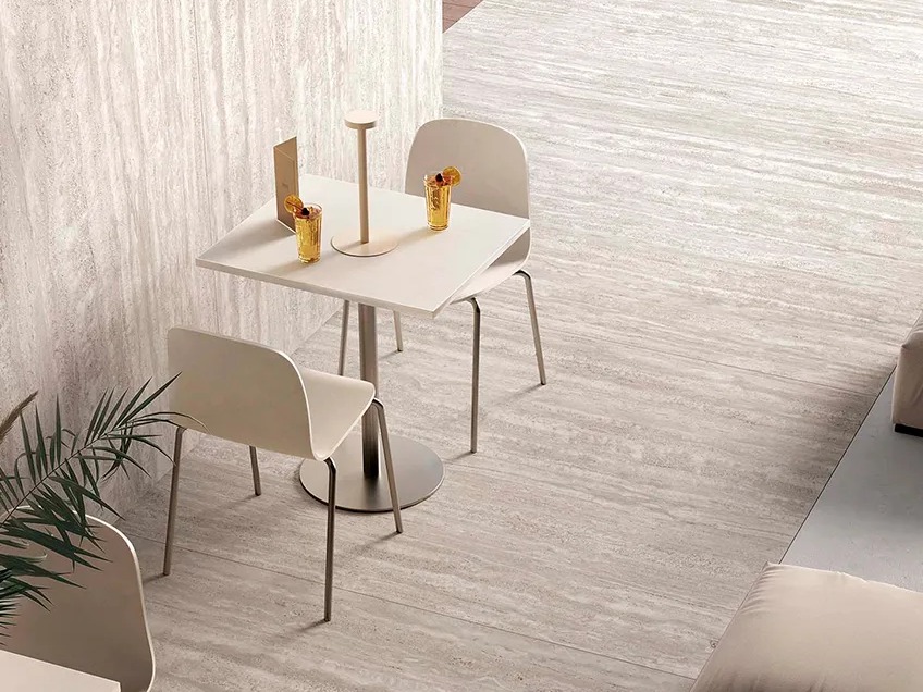 Cafe seating area with Travertino Chiaro porcelain slabs on floor and wall with white chairs.