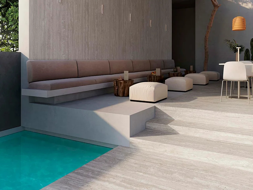 Outdoor poolside lounge featuring Travertino Chiaro porcelain slabs on floor and steps with seating area.
