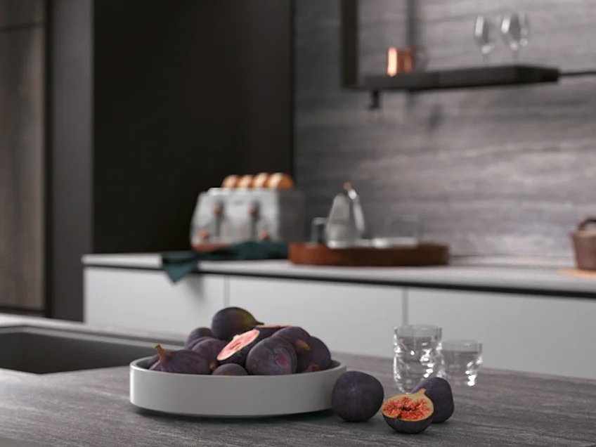 Modern kitchen with Travertino Grey porcelain slabs on backsplash and dark cabinetry with fresh figs.