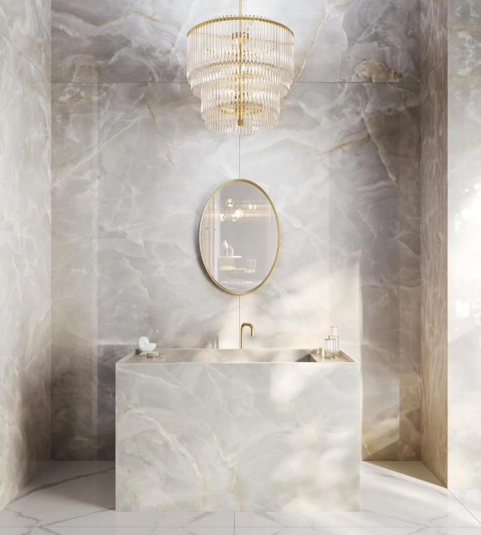 Elegant bathroom design showcasing Onyx White porcelain slabs with crystal chandelier and gold fixtures.