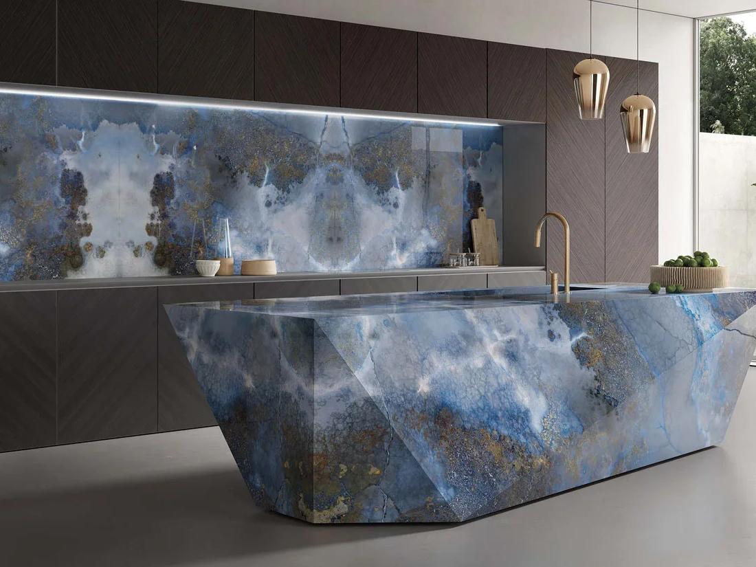 Luxury kitchen showcasing Thunderstorm porcelain slabs on island and backsplash with gold fixtures.