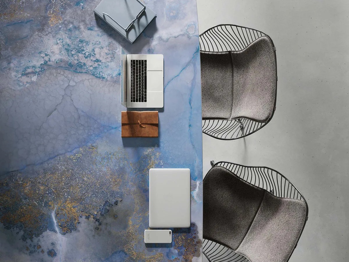 Thunderstorm porcelain slabs sample displayed with modern furniture and accessories on grey concrete surface.