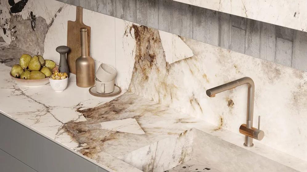 Kitchen countertop and backsplash featuring Magellano porcelain slabs with bronze faucet fixture.