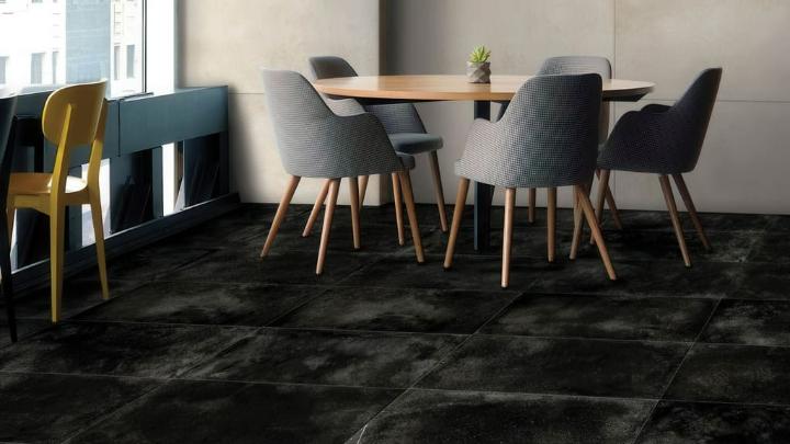 Contemporary dining space featuring a wood table, gray upholstered chairs, and dark textured flooring Modern dining area with wooden table and upholstered chairs