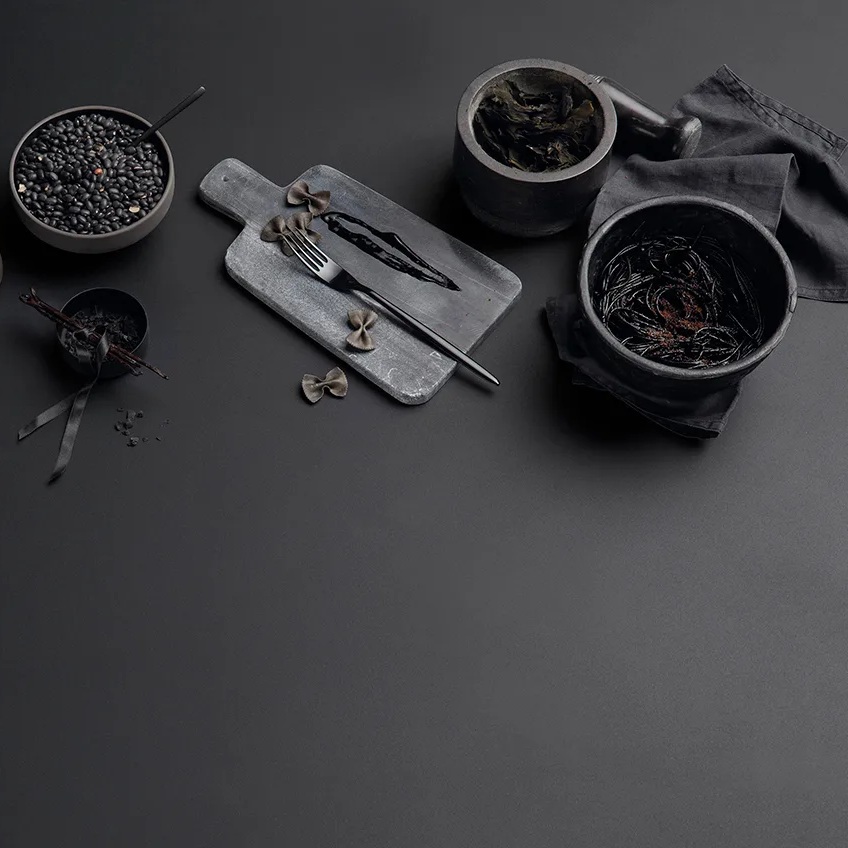 Absolute Black porcelain slabs surface with cutting board, bowls, and scattered coffee beans styling.
