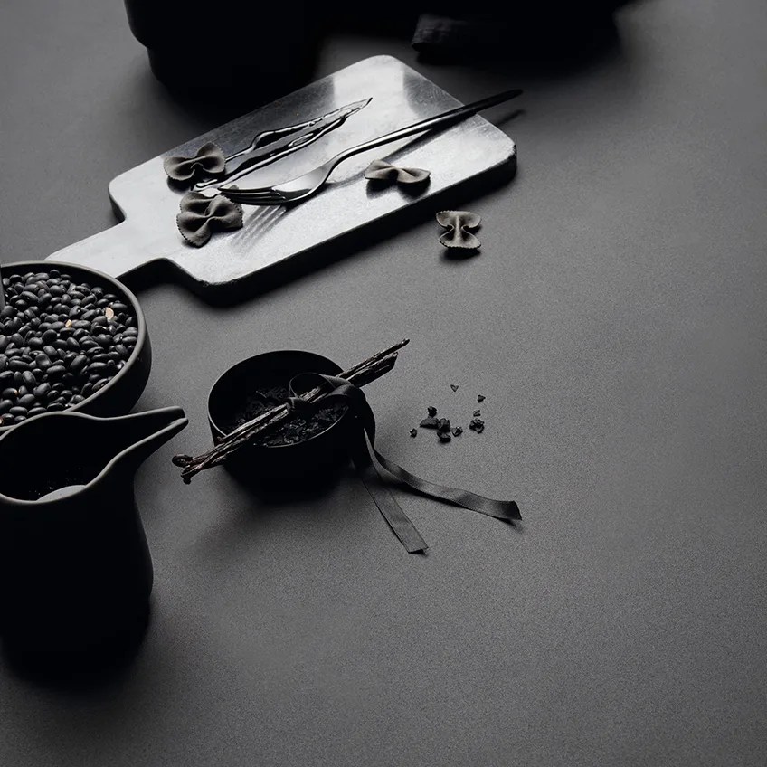 Absolute Black porcelain slabs tabletop styled with cutting board and scattered coffee beans.