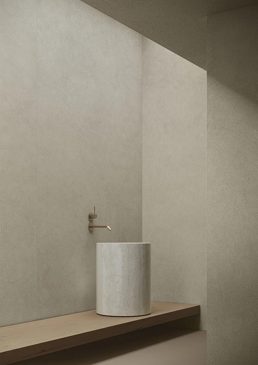 Plaster Bone porcelain slabs bathroom wall with pedestal sink and wooden platform.