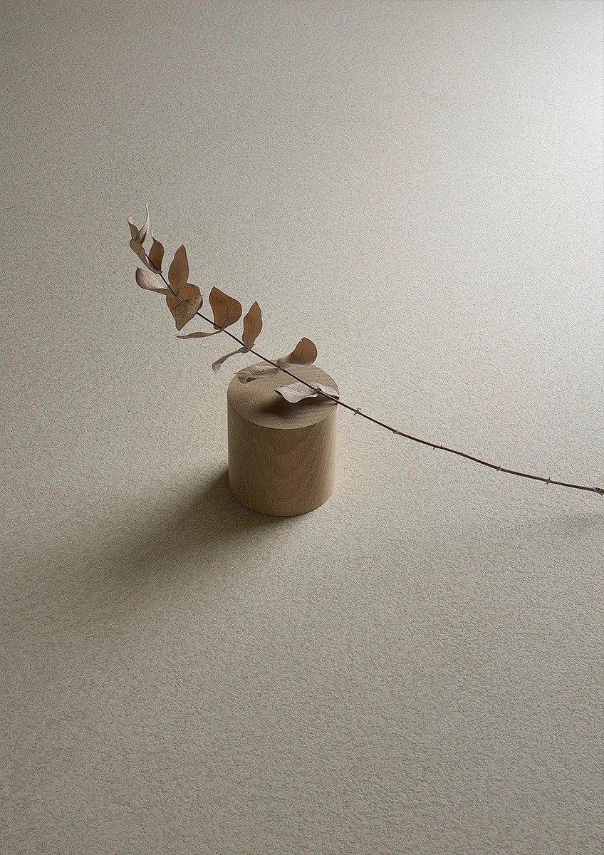 Plaster Bone porcelain slabs wall with decorative vase and dried eucalyptus branch detail.
