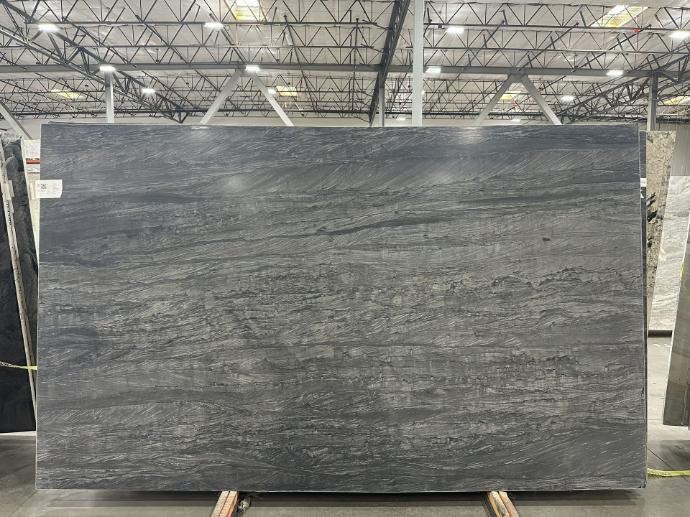 Gray quartzite slab with natural wave-like veining displayed in stone warehouse