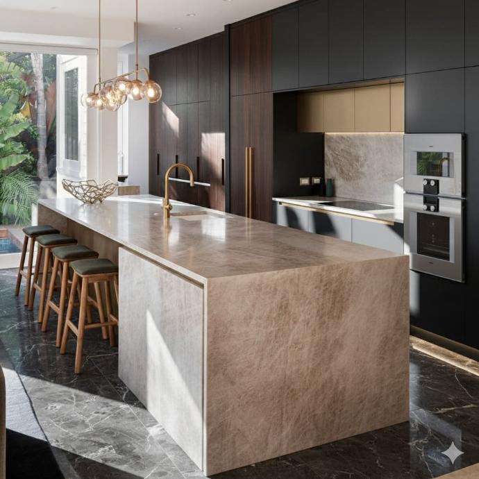 A modern luxury kitchen featuring a large stone waterfall island with a gold faucet, dark minimalist cabinetry, and four wooden bar stools under warm, elegant lighting
