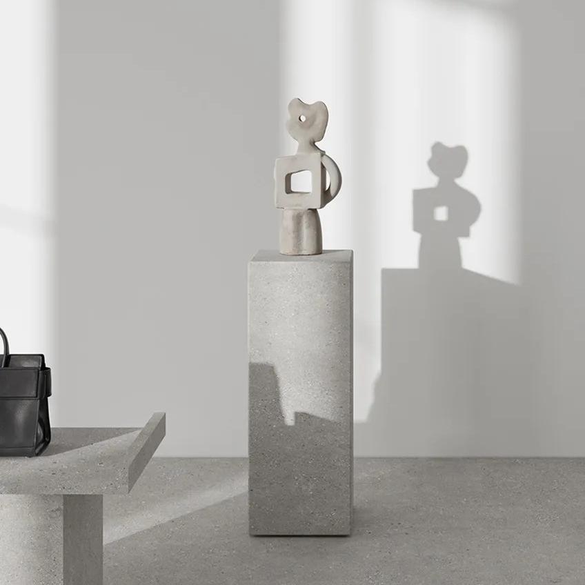 Minimalist interior display featuring Sandstone Light porcelain slabs with sculptural decor and natural lighting.