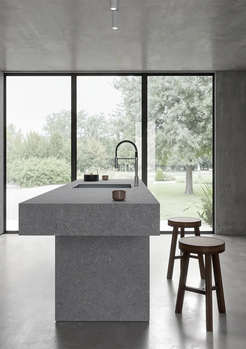 Modern kitchen island made with Sandstone Gray porcelain slabs in bright space.