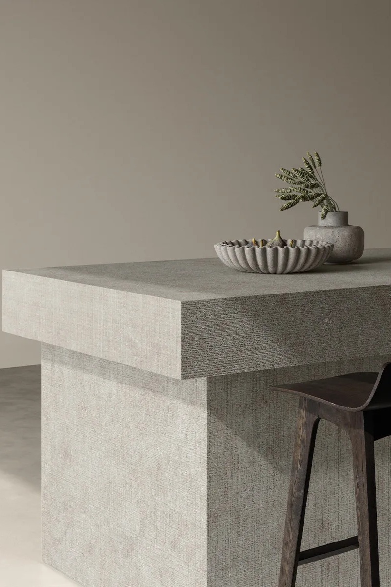 Fossil Row porcelain slabs used as a kitchen island countertop with a wooden stool.