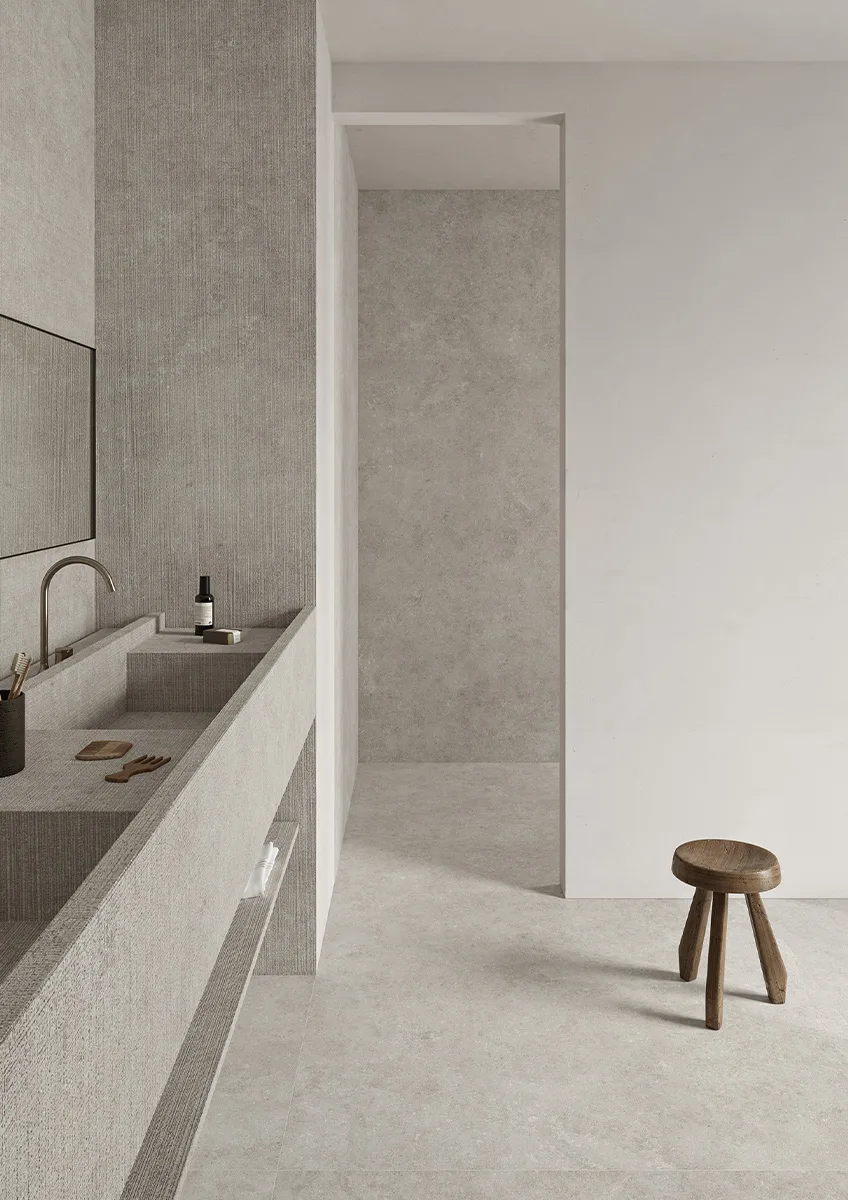 Spa bathroom with Fossil porcelain slabs on walls and natural wood accent stool.