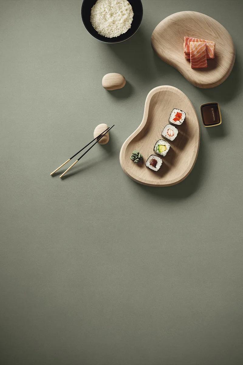 Chopsticks and sushi placed on Gordes porcelain slabs showing smooth sage green matte finish.