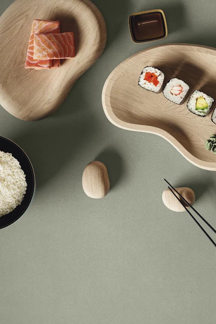 Overhead view of sushi and rice bowls arranged on sage green Gordes porcelain slabs.