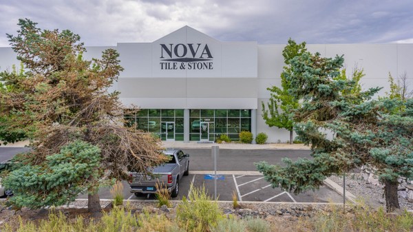 Outside view of Nova Tile and Stone building with trees and a truck parked outside