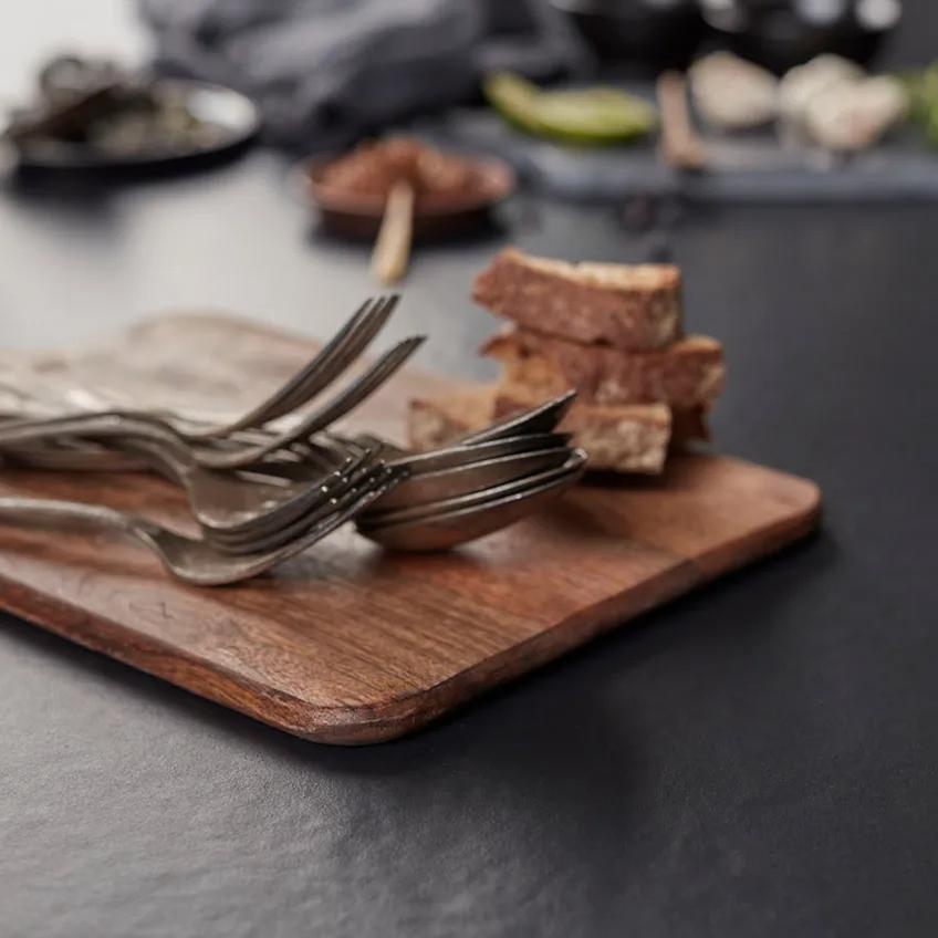 Rustic bread and silver forks on a wood board over Pigalle porcelain slabs.