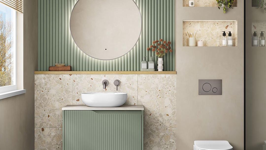 shorter Modern bathroom with a sage green fluted vanity, circular backlit mirror, speckled tile backsplash, and a light and green diamond-patterned floor.