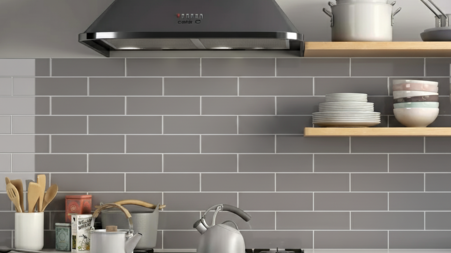 Kitchen view with a dark grey cooker hood above a stainless steel range, and grey subway tile backsplash