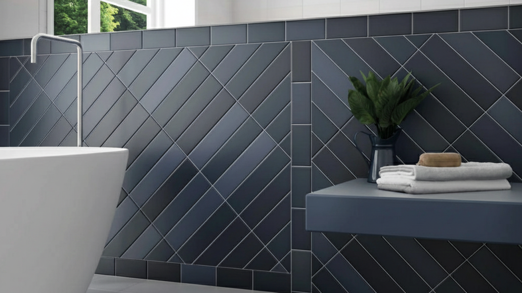 Close-up of a decorative tile feature wall in a bathroom, using dark blue tiles laid in a striking diagonal pattern and framed to create panels.